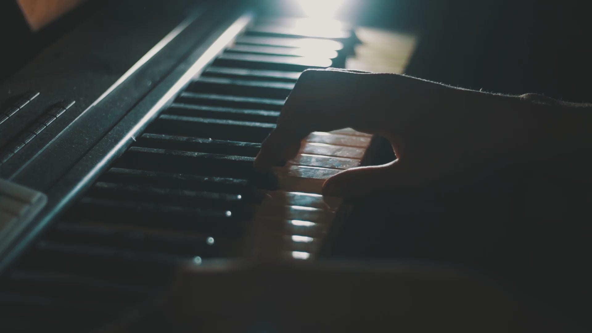 Hand playing piano with sun shining on the keys